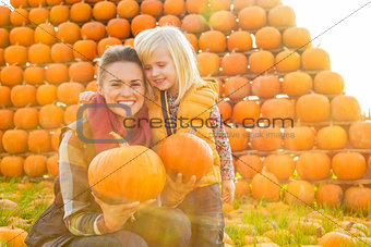 Portrait of happy mother and child holding pumpkins