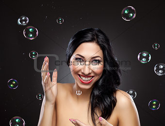 Young and happy woman surrounded by bubbles