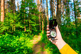 female hand holding a compass in the forest