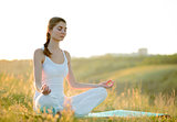 Young Beautiful Woman Practices Yoga on the Sunny Meadow