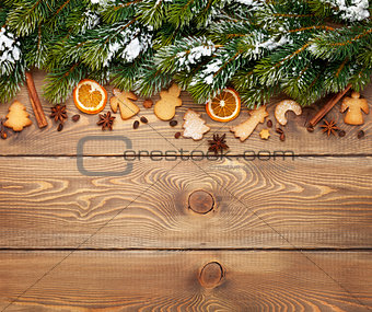 Christmas wooden background with snow fir tree, spices, gingerbr
