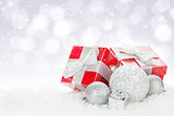 Christmas baubles and red gift boxes over snow bokeh background