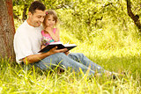 young father with his little daughter reads the Bible