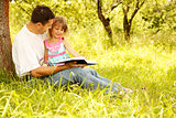 young father with his little daughter reads the Bible