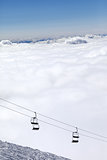 Ski slope, chair-lift and mountains under clouds