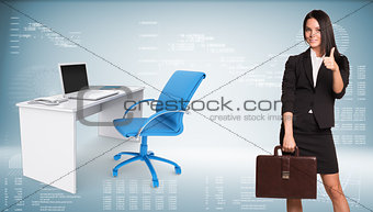 Businesswoman showing thumb-up. Office table with chair and laptop are located next