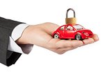 toy car with lock on top in the hand of business man concept for insurance, buying, renting, fuel or service and repair costs 