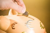 hand inserting a coin into a piggy bank, concept for business and save money