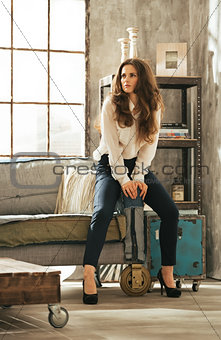 Full length portrait of young woman sitting on couch in loft apa