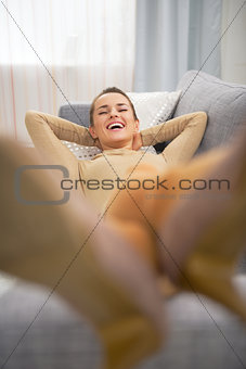 Happy young woman laying on couch in living room