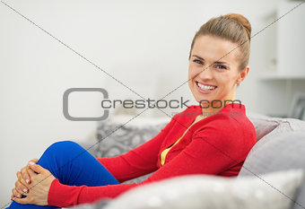Portrait of happy young woman sitting on divan