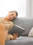 Young woman sitting on sofa and using tablet pc