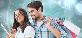 Composite image of happy couple with shopping bags and tablet