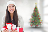 Composite image of festive brunette holding gifts