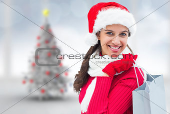 Composite image of festive brunette holding shopping bag