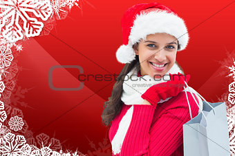 Composite image of festive brunette holding shopping bag