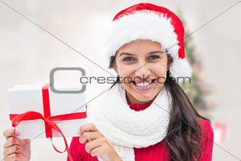 Composite image of festive brunette holding gift