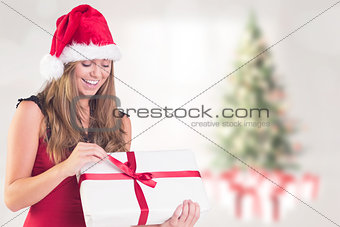 Composite image of festive blonde opening a gift