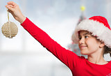 Composite image of festive girl hanging decoration