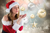Composite image of sexy santa girl blowing over hands