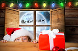 Composite image of festive boy peeking over table