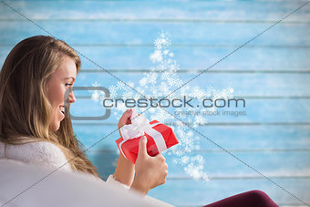 Composite image of pretty blonde relaxing on the couch with gift