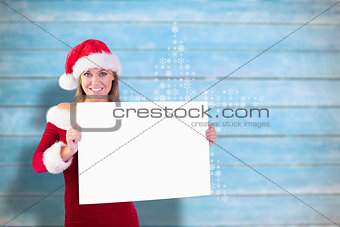 Composite image of festive blonde smiling at camera holding poster