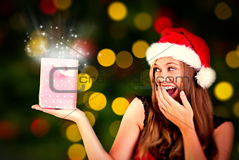 Composite image of festive blonde holding a gift bag
