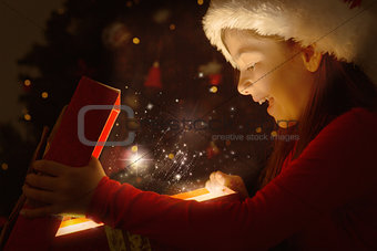 Composite image of little girl opening a magical christmas gift