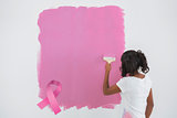 Composite image of young woman painting her wall in pink