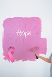 Composite image of woman painting her wall pink