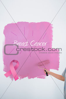 Composite image of woman painting her wall pink