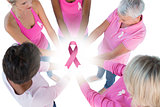 Composite image of group wearing pink and ribbons for breast cancer with hands together