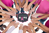 Composite image of hands joined in circle wearing pink for breast cancer