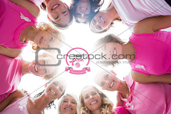 Composite image of cheerful women in circle wearing pink for breast cancer