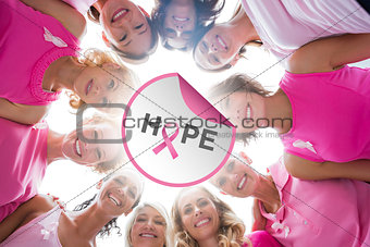Composite image of cheerful women in circle wearing pink for breast cancer