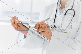 Composite image of mid section of a female doctor writing reports