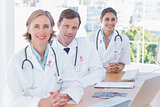 Composite image of smiling doctors posing at their desk