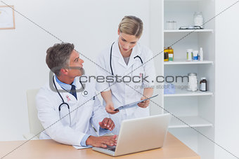 Composite image of nurse showing a folder to her colleague