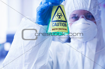 Scientist in protective suit holding beaker
