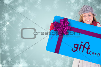 Composite image of happy blonde in winter clothes showing card