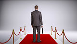 Businessman in suit holding briefcase and standing on red carpet. Rear view
