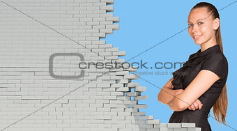 Beautiful businesswoman in dress smiling and looking at camera. Dilapidated brick wall as backdrop
