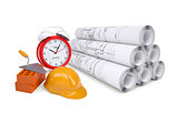 Scrolls of architectural drawings and alarm clock with work tools