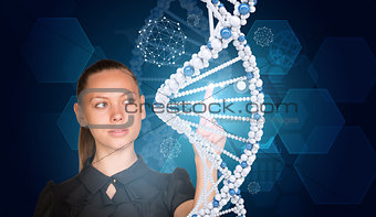 Beautiful businesswoman in dress presses finger on model of DNA