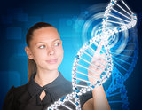 Beautiful businesswoman in dress smiling and presses finger on model of DNA