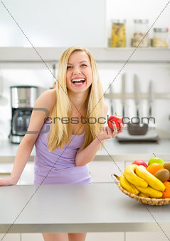 Portrait of smiling young woman with apple in modern kitchen