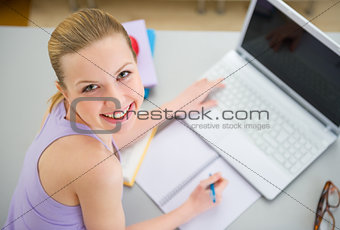 Happy young woman studying in kitchen