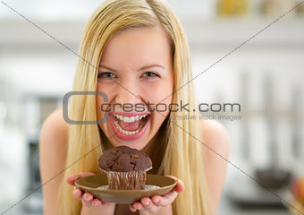 Portrait of happy young woman holding muffin