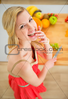 Portrait of happy young woman cutting fruits in kitchen
